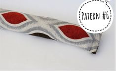 a red and gray pillow sitting on top of a white table next to a tag that says pattern 6