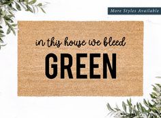 a door mat with the words in this house we bleed green on it and leaves