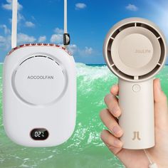 a person holding an air freshener and a portable fan in front of the ocean