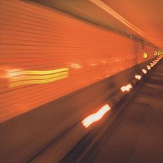 a blurry photo of a train going down the tracks in an underground tunnel at night