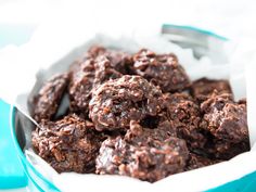 a bowl filled with chocolate treats on top of a blue table cloth next to a metal spoon