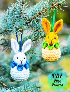 two crocheted easter bunnies hanging from a pine tree with blue and white ribbons