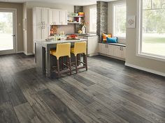 a kitchen with wood flooring and white cabinetry, two yellow stools at the center island