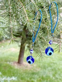 two blue glass beads hanging from a tree branch