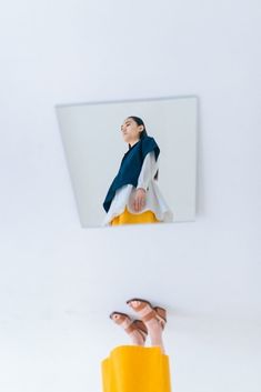 a woman's feet are shown in front of a white wall with a mirror above her