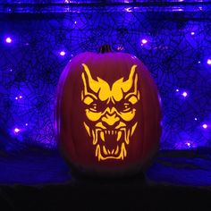 a carved pumpkin with an evil face on it in front of purple and blue lights