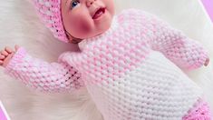 a baby wearing a pink and white knitted outfit