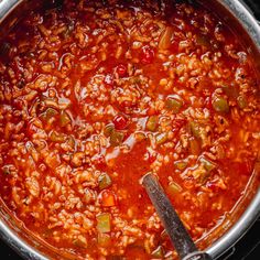 a large pot filled with lots of food on top of a stove next to a wooden spoon