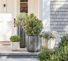 three large metal planters sitting on the steps in front of a house