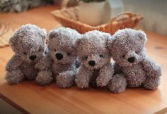 four teddy bears sitting on top of a wooden table