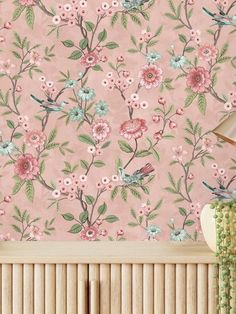 a pink wallpaper with flowers and birds on it, next to a radiator