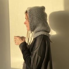 a woman wearing a knitted hat and holding a cup