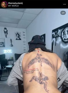 a person with a tattoo on their back sitting in front of a chair and looking at the camera