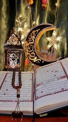 an open book sitting on top of a wooden table next to a clock and lamp