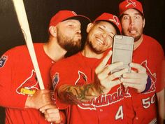 three baseball players are taking a selfie with their cell phone while posing for the camera