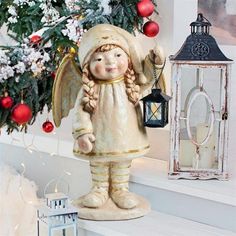 an angel figurine holding a lantern next to a christmas tree