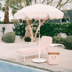 an umbrella sitting next to a pool with a chair and cooler on it's side