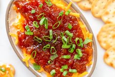 a plate with crackers, cheese and ketchup on it next to crackers