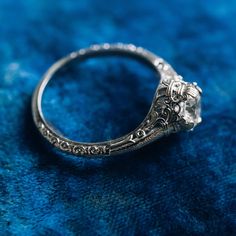 an antique style engagement ring on blue velvet