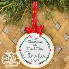 a cross stitch ornament hanging from a christmas tree with a red ribbon on it