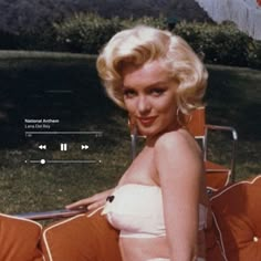 a woman sitting on top of an orange chair next to a green grass covered field