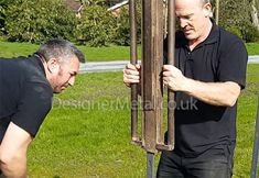 two men are working on something outside in the grass and one man is holding it up