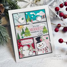 a christmas card with snowmen and evergreens on the table next to some red berries