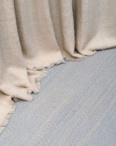 the corner of a blue carpeted room with a white blanket on top of it