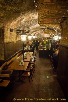 people are sitting at tables in the middle of a long room with exposed brick walls