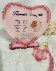 a pink heart shaped plaque with a baby's photo on it