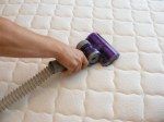 a person using a vacuum to clean a mattress