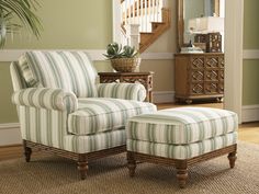 a striped chair and ottoman in a living room with green walls, hardwood floors and stairs