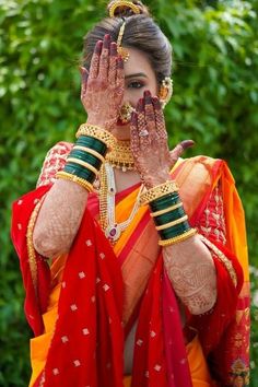 a woman in red and yellow sari holding her hands up to her face with both hands