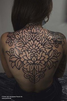 the back of a woman's shoulder with an intricate tattoo design on it