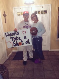 a man and woman standing in front of a door holding a sign