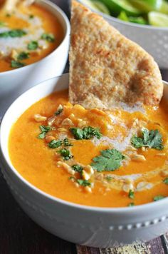 two bowls filled with soup and pita bread on top of each other next to green beans