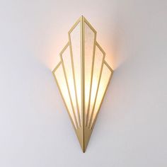 a wall light that is on the side of a white wall with gold trimmings