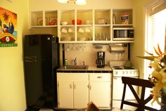 a small kitchen with black and white checkerboard flooring, cabinets, microwave, stove top oven and refrigerator