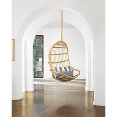 a hanging chair in the middle of a room with an arched doorway and wood floors