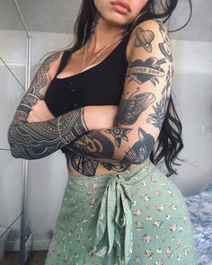 a woman with tattoos on her arms posing for the camera