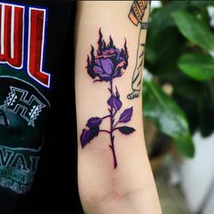 a purple rose tattoo on the left arm