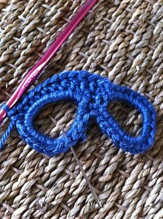 a pair of blue scissors sitting on top of a woven piece of cloth next to a knitting needle