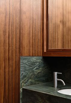 a bathroom with wooden cabinets and a white sink under a faucet mounted on the wall