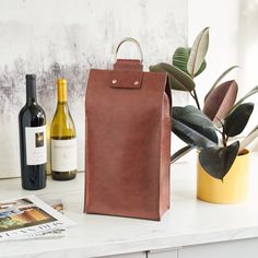 a brown leather bag sitting on top of a white counter next to bottles of wine