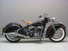 a black and red motorcycle parked on top of a white floor next to a gray wall