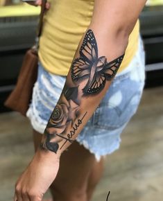 a woman's arm with a butterfly and roses tattoo on the left side of her arm