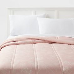 a bed with white pillows and pink comforter