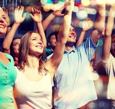 a group of people standing next to each other holding their hands up in the air