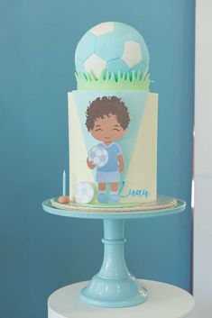 a birthday cake with a boy holding a soccer ball on it's top tier