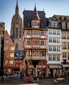 an old building in the middle of town with people walking around it and buildings on both sides